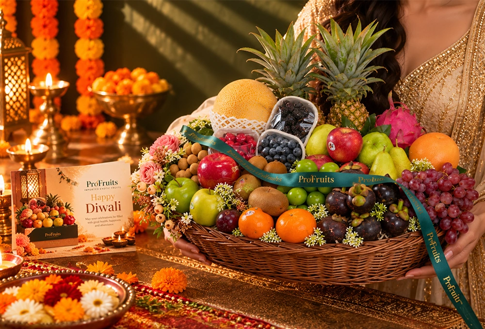 Green Apple, Murcott Orange, Golden Kiwi, Red Ice Guava, China Plum, Green Muscat Grapes, Mangosteen, Green Vermont Pear, Red Apple, Grapefruit, Pink Guava, Red Seedless Grapes, Kutch Dragon Fruit, Blueberries, Mulberries, Raspberries, Longan, Whole Pineapple, Golden Emerald Muskmelon, and Avocado with a Basket & Diwali Greeting Card.